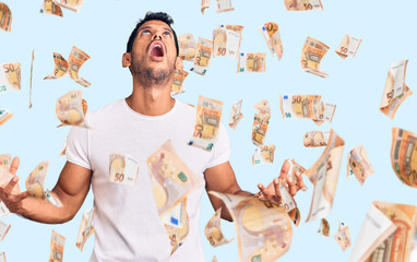 Young latin man wearing casual clothes crazy and mad shouting and yelling with aggressive...