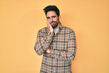 Handsome hispanic man with beard wearing casual clothes thinking looking tired and bored with depression problems with crossed arms.