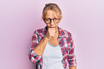 Middle age blonde woman wearing casual clothes and glasses feeling unwell and coughing as symptom...