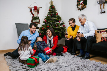 Latin family with children and grandparents sharing Christmas gifts in Mexico
