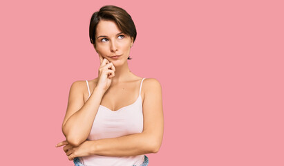 Young brunette woman with short hair wearing casual summer clothes serious face thinking about...