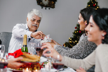 Latin old man eating on a Christmas decorated mexican house