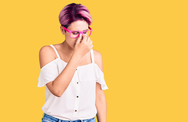 Young beautiful woman with pink hair wearing casual clothes and glasses tired rubbing nose and eyes feeling fatigue and headache. stress and frustration concept.