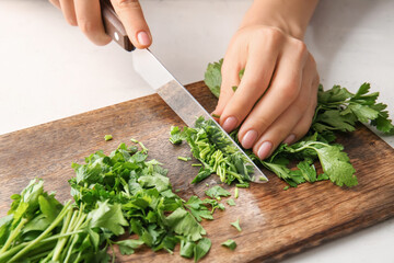 Woman cutting fresh parsley at table, closeup