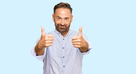 Handsome middle age man wearing business shirt approving doing positive gesture with hand, thumbs up smiling and happy for success. winner gesture.