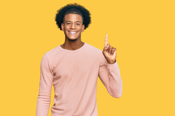 African american man with afro hair wearing casual clothes showing and pointing up with finger number one while smiling confident and happy.