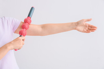 Sportswoman massaging herself with body roller on light background