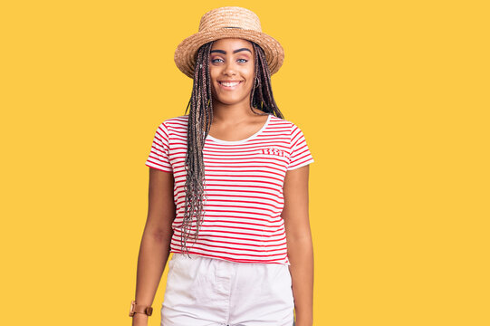 Young african american woman with braids wearing summer hat with a happy and cool smile on face. lucky person.