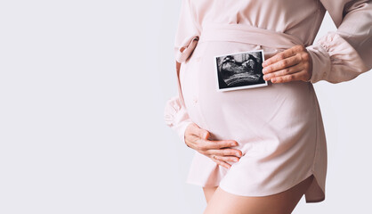 Pregnant woman holding ultrasound baby image.