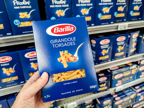 Closeup of Man hand buying a package of girandole torsades pasta Barilla brand display for sell in french supermarket