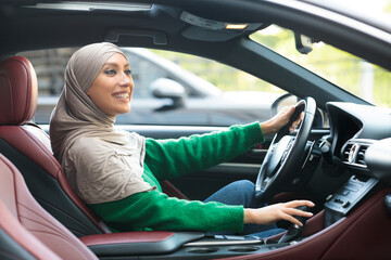 Smiling muslim woman driving her new car in city