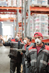 Serious middle aged Latino male worker in uniform and protective respirator