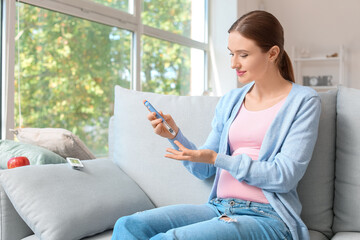 Obraz premium Pregnant diabetic woman taking blood sample with lancet pen at home