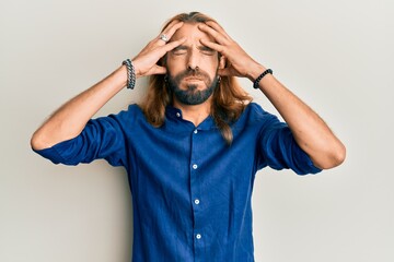 Attractive man with long hair and beard wearing casual clothes with hand on head, headache because stress. suffering migraine.