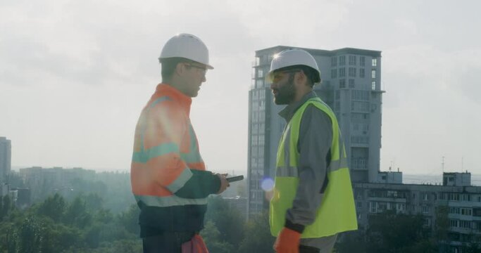 Contactors with tablet talking on top of building