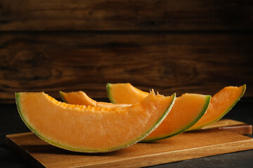 Slices of tasty fresh melon on black table, closeup