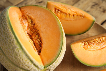 Tasty fresh cut melons on wooden tray, closeup
