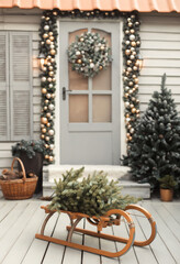 House christmas decorations in gold and silver colors. Сhristmas wreath on the door. Sled with tree