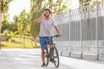 Male cyclist talking by phone outdoors