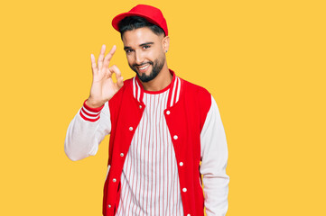 Young man with beard wearing baseball uniform smiling positive doing ok sign with hand and fingers. successful expression.