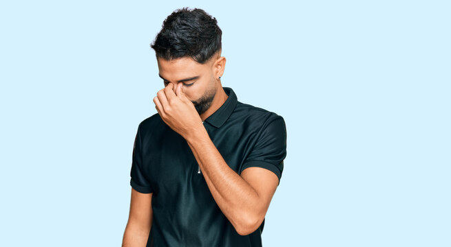 Young man with beard wearing sportswear tired rubbing nose and eyes feeling fatigue and headache. stress and frustration concept.