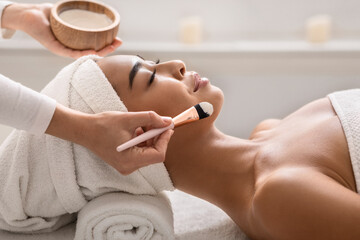 Obraz na płótnie Canvas Beauty therapist applying face mask on young asian female skin at spa