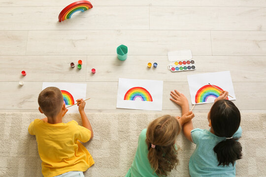 Little children painting rainbow  during Covid-19 quarantine at home, top view