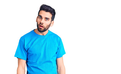 Young handsome man with beard wearing casual t-shirt in shock face, looking skeptical and sarcastic, surprised with open mouth