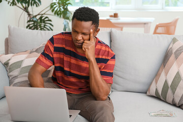 Stressed African-American man with laptop at home