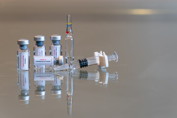 A quadruple set of mini vials of COVID-19 Coronvavirus vaccine with a syringe on the right and an ampule in the rear - 135