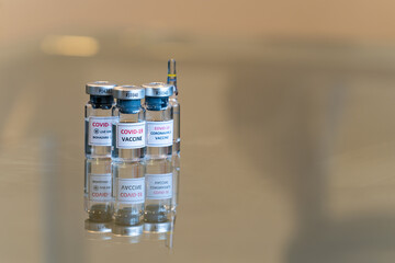 A set of three COVID-19 vaccination drug dose trial vials with a test ampule in the rear and with added copy space - 004