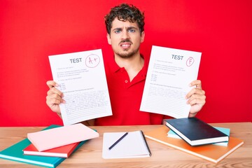 Young caucasian man with curly hair showing a passed exam sitting on the table clueless and confused expression. doubt concept.