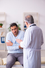 Obraz premium Young sick man visiting old doctor