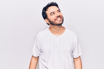 Young hispanic man wearing casual clothes looking away to side with smile on face, natural expression. laughing confident.