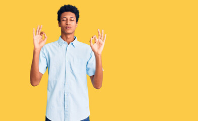 Young african american man wearing casual clothes relaxed and smiling with eyes closed doing meditation gesture with fingers. yoga concept.