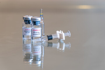A closeup double vial set of COVID-19 Coronvavirus live virus biohazard culture with a syringe on the right and needle tip in the front - 122