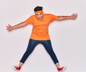 Adorable hispanic kid wearing sportswear smiling happy. Jumping with smile on face over isolated white background