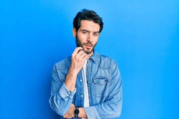Young hispanic man wearing casual clothes thinking concentrated about doubt with finger on chin and looking up wondering