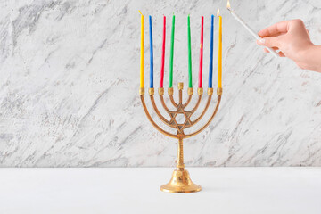 Woman lighting candles on menorah for Hanukkah on white background