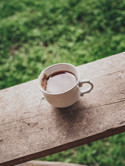 Top view, Tea cup on the wooden table in morning and green field mountain background. Nature picture and space for text. Organic product from the nature for healthy. Vertical  and grain picture.