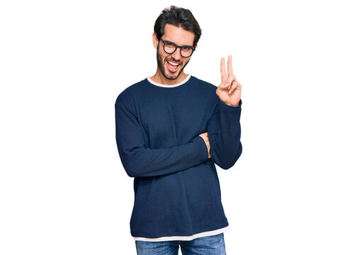Young hispanic man wearing casual clothes and glasses smiling with happy face winking at the camera doing victory sign. number two.