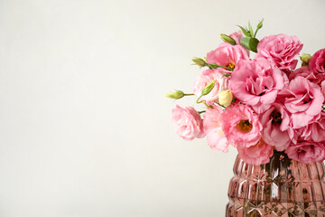 Beautiful pink Eustoma flowers in vase on light background. Space for text