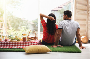 Couple imitating picnic at home, back view