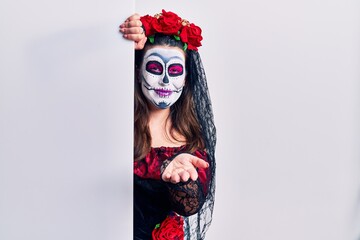Young woman wearing day of the dead custome holding blank empty banner smiling cheerful offering palm hand giving assistance and acceptance.
