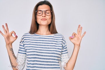 Beautiful caucasian woman wearing casual clothes and glasses relax and smiling with eyes closed doing meditation gesture with fingers. yoga concept.