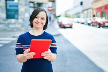 Beautiful brunette woman with down syndrome at the town on a sunny day using touchpad device