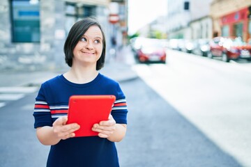 Beautiful brunette woman with down syndrome at the town on a sunny day using touchpad device