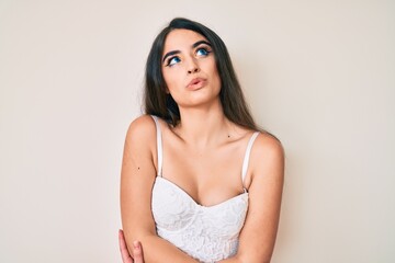 Brunette teenager girl posing elegant smiling looking to the side and staring away thinking.