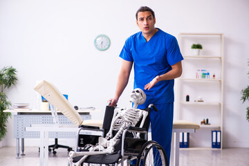 Young male doctor and skeleton in wheel-chair