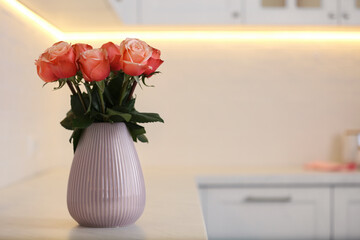 Vase with beautiful roses on countertop in kitchen, space for text. Interior design